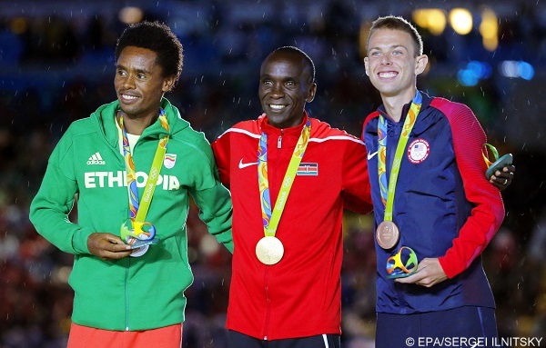 epa05506266 Eliud Kipchoge (C) of Kenya poses with his gold medal on the podium after winning the men's Marathon race of the Rio 2016 Olympic Games Athletics, Track and Field events at the Sambodromo in Rio de Janeiro, Brazil, 21 August 2016. Kipchoge won ahead of second placed Feyisa Lilesa (L) of Ethiopia and third placed Galen Rupp (R) of the USA.  EPA/SERGEI ILNITSKY